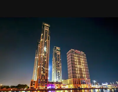 two tall buildings are lit up at night at Skyline & Islands View 3BR Luxe Top Floor Noura Tower Business Bay in Dubai