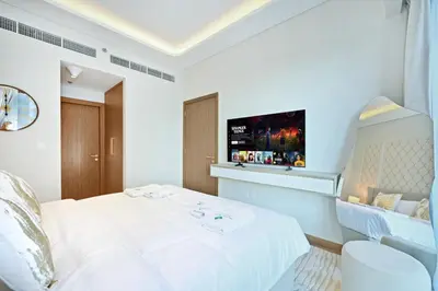 a bedroom with a white bed with a tv on the wall at Bloomfields Grandeur 2BR in Azizi Riviera in Dubai