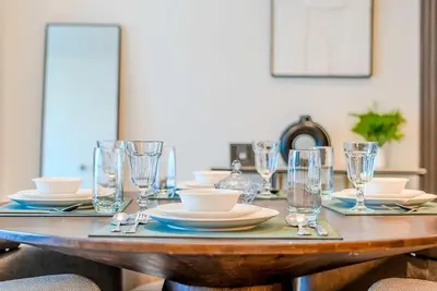 a wooden table with plates and glasses on it at TRPS - Burj Crown, Downtown - Skyline and Pool View, Furnished, Downtown in Dubai
