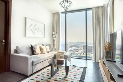 a living room with a couch and a large window at Frank Porter - The Crest Tower, Sobha Hartland in Dubai