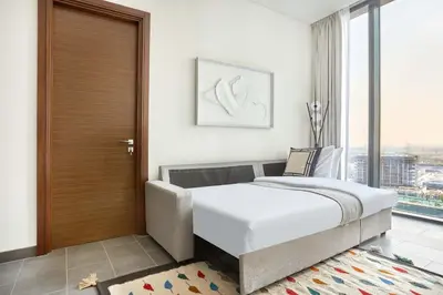 a bedroom with a bed and a wooden door at Frank Porter - The Crest Tower, Sobha Hartland in Dubai