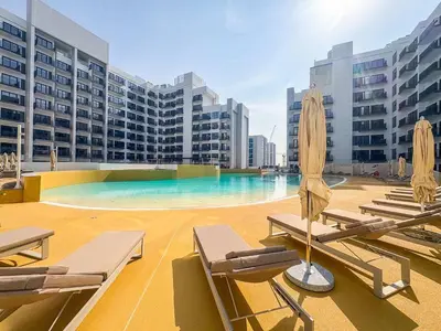 a swimming pool with lounge chairs and umbrellas on a building at Frank Porter - Azizi Beach Oasis in Dubai