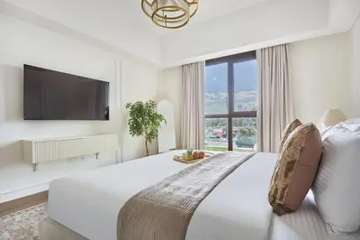 a white bedroom with a large bed and a large window at Frank Porter - Al Jazi in Dubai