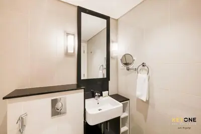 a white bathroom with a sink and a mirror at The Cosmopolitan Spacious Studio in Dubai