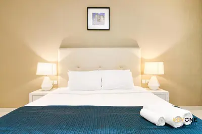 a bedroom with a large white bed with two lamps at The Cosmopolitan Spacious Studio in Dubai