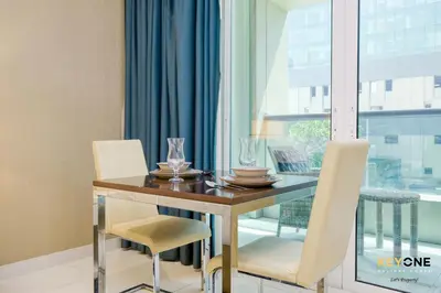 a dining room with a table and chairs and a window at The Cosmopolitan Spacious Studio in Dubai