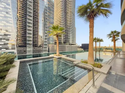 a swimming pool with palm trees and buildings at FIRST CLASS 2BR Vibrant Next to Dubai Mall in Dubai