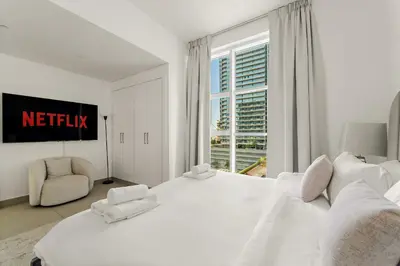 a white bedroom with a large bed and a window at VayK - Stylish 2BD in Dubai Marina Near the Beach in Dubai