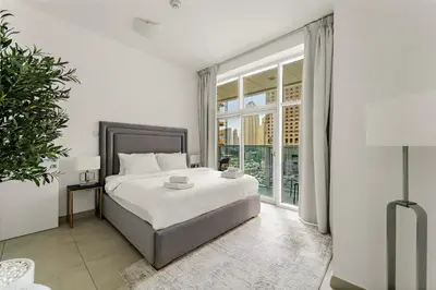 a white bedroom with a bed and a large window at VayK - Stylish 2BD in Dubai Marina Near the Beach in Dubai
