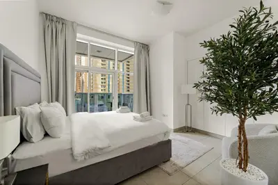 a bedroom with a large bed and a window at VayK - Stylish 2BD in Dubai Marina Near the Beach in Dubai