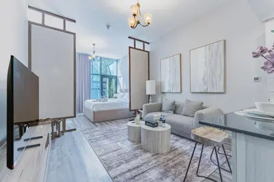 a living room with a couch and a tv at Stylish Studio in JVC with Pool and Gym Access in Dubai