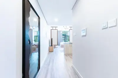 a hallway with white walls and a large mirror at Stylish Studio in JVC with Pool and Gym Access in Dubai