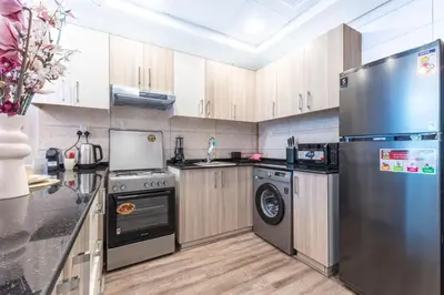 a kitchen with a stainless steel refrigerator and a dishwasher at Stylish Studio in JVC with Pool and Gym Access in Dubai