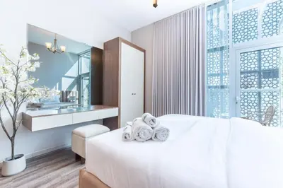 a bedroom with a white bed with a sink and a mirror at Stylish Studio in JVC with Pool and Gym Access in Dubai