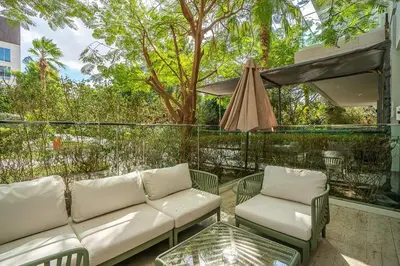 a patio with a couch and chairs and an umbrella at Serene Studio in Al Barari Near Dubai Hills Mall in Dubai