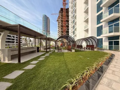 a park with benches and grass in front of a building at GuestReady - Studio Suite l Community Jacuzzi in Dubai