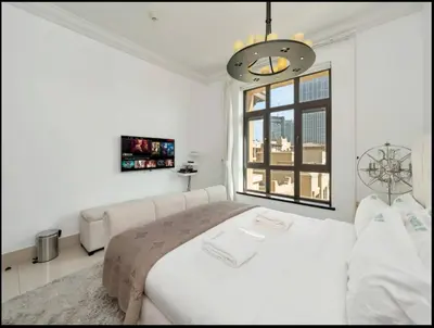 a white bedroom with a large bed and a window at Skyline Souk 1 & 2 Bedroom Apartments I Burj Khalifa Views I Private Terrace I Gym, Pool, Parking & Wi-Fi in Dubai