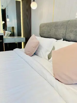 a bed with white sheets and a pink pillow on it at Modern Studio With Scenic Views in Dubai