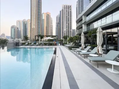 a swimming pool with chairs and umbrellas on a building at Luxurious Apartment in Downtown near Burj Khalifa in Dubai