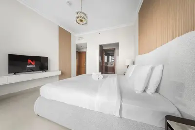 a white bedroom with a white bed and a tv at Luxurious Apartment with Burj Khalifa View in Downtown in Dubai