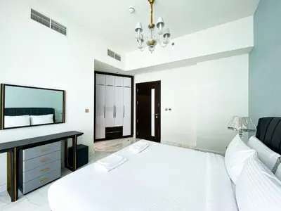 a white bedroom with a bed and a desk at Elegant 1BDR Sleeps 4 in Bayz-22 in Dubai