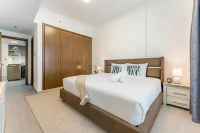 a bedroom with a large bed and a wooden cabinet at Compact 1BR, Just A Minute Drive to At the Top Burj Khalifa - Ontario Tower, Business Bay in Dubai