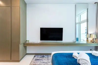 a bedroom with a tv and a bed with blue sheets at PVH - Damac Maison Prive - Studio with Canal and Pool View in Dubai