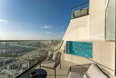 a balcony with chairs and a swimming pool on a building at HAVN - High floor 1BR with Private Sky Pool, JVC in Dubai