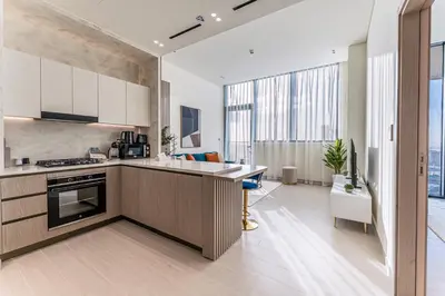 a kitchen with white cabinets and a large window at HAVN - High floor 1BR with Private Sky Pool, JVC in Dubai