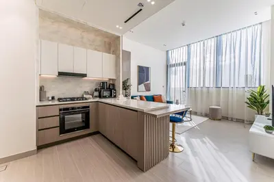 a kitchen with white cabinets and a large window at HAVN - High floor 1BR with Private Sky Pool, JVC in Dubai