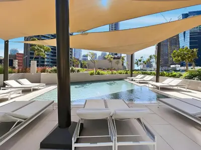 a swimming pool with white chairs and a large umbrella at Stylish 1BR Apartment Peninsula One Business Bay in Dubai