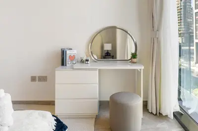 a white dressing table with a mirror and a stool at Stylish 1BR Apartment Peninsula One Business Bay in Dubai