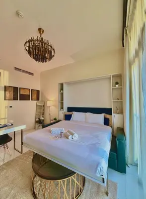 a bedroom with a large bed and a desk at Chic Studio near Miracle Garden & GlobalVillage in Dubai