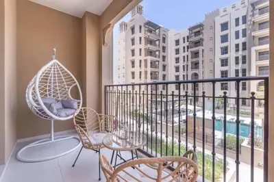 a balcony with chairs and a table and a swing at Vogue Madinat Jumeirah Living Jadeel near Burj AlArab, One-Bedroom Apartment with Large Balcony and Pool View, Access to All Amenities in Dubai