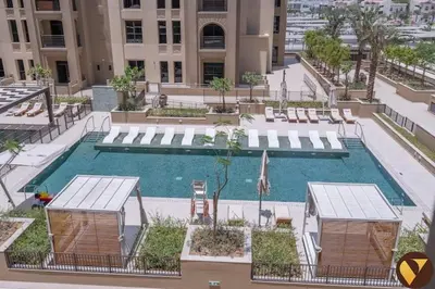 a large swimming pool with chairs and a building at Vogue Madinat Jumeirah Living Jadeel near Burj AlArab, One-Bedroom Apartment with Large Balcony and Pool View, Access to All Amenities in Dubai