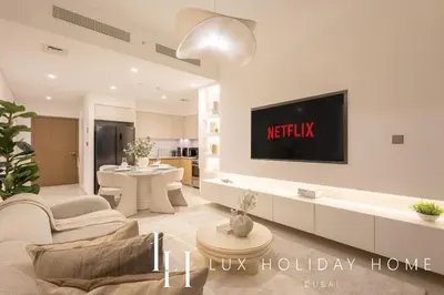 a living room with a tv on a wall at LUX 2BR High Floor - Near Dubai Mall in Dubai