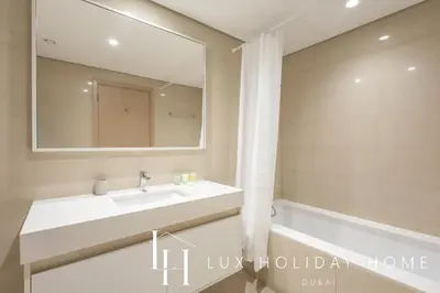 a bathroom with a sink and a mirror and a tub at LUX 2BR High Floor - Near Dubai Mall in Dubai