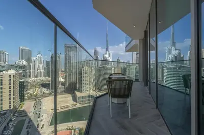 a chair on a balcony with a view of a city at Mystic - Luxe 1BR Apt with Burj Khalifa & Canal Views in Dubai