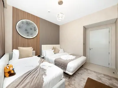 a bedroom with two beds and a clock on the wall at Luxury 4BR Villa in Arabian Ranches 3, Resort-Style Living with Private Garden & Hot Tub in Nadd Shubayḩ