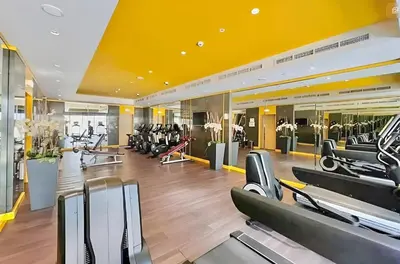 a gym with several treadmills and elliptical machines at Modern 1BR Apartment in DAMAC Merano Business Bay in Dubai