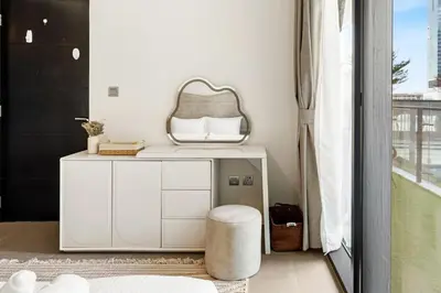 a white dressing table with a stool and a mirror at Modern 1BR Apartment in DAMAC Merano Business Bay in Dubai