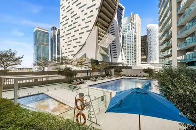 a pool with an umbrella and some buildings at Modern 1BR Apartment in DAMAC Merano Business Bay in Dubai