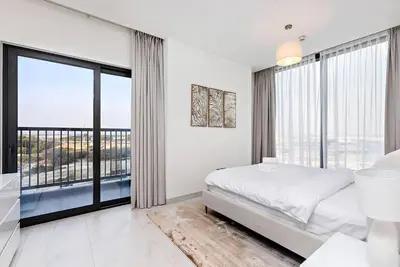 a white bedroom with a bed and large windows at Premium 3BR Study in Sobha Hartland in Dubai