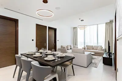 a dining room with a table and a living room at Premium 3BR Study in Sobha Hartland in Dubai