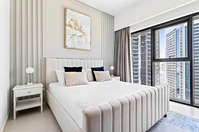 a white bedroom with a large bed and a window at Silkhaus Prime 1BDR in Burj Royale in Dubai