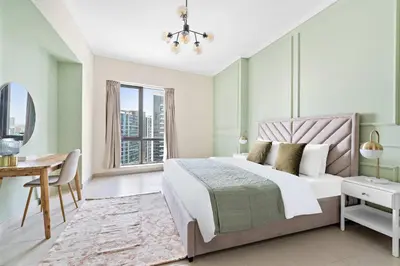 a bedroom with a bed and a desk and a window at Silkhaus 1 BDR in South Ridge on High Floor in Dubai