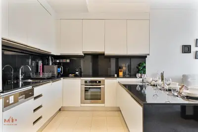 a kitchen with white cabinets and black counter tops at Luxury 1 Bed in Marina Mall JW Marriot in Dubai