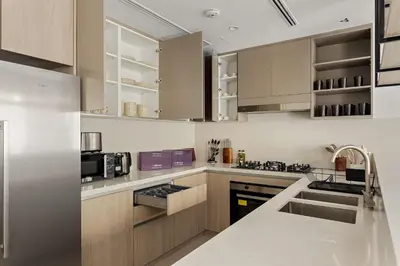 a kitchen with stainless steel appliances and wooden cabinets at Silkhaus Spacious 3BDR & Maid Tilal Al Ghaf in Dubai