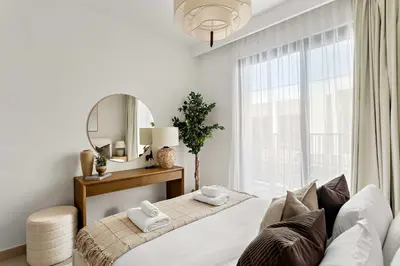 a white bedroom with a bed and a mirror at Silkhaus Spacious 3BDR & Maid Tilal Al Ghaf in Dubai
