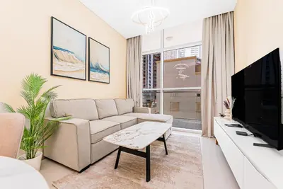 a living room with a couch and a tv at Escape 24 Stylish 1BR in Artesia, Pool & Gym, Damac Hills in Dubai